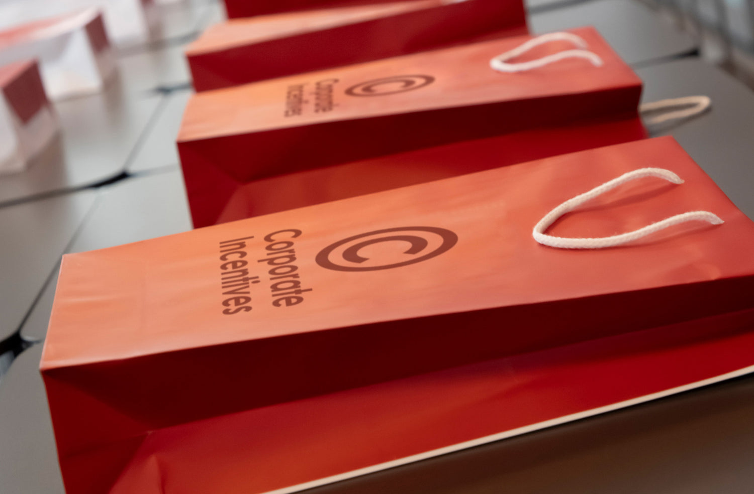 Red gift bags with a logo and text on a reflective surface