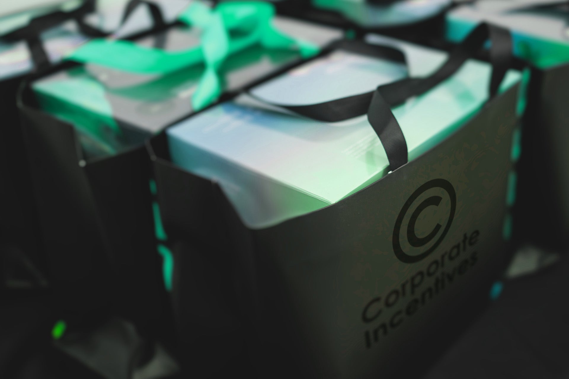 Black bags with green ribbons and 'Corporate Incentives' logo on a blurred background